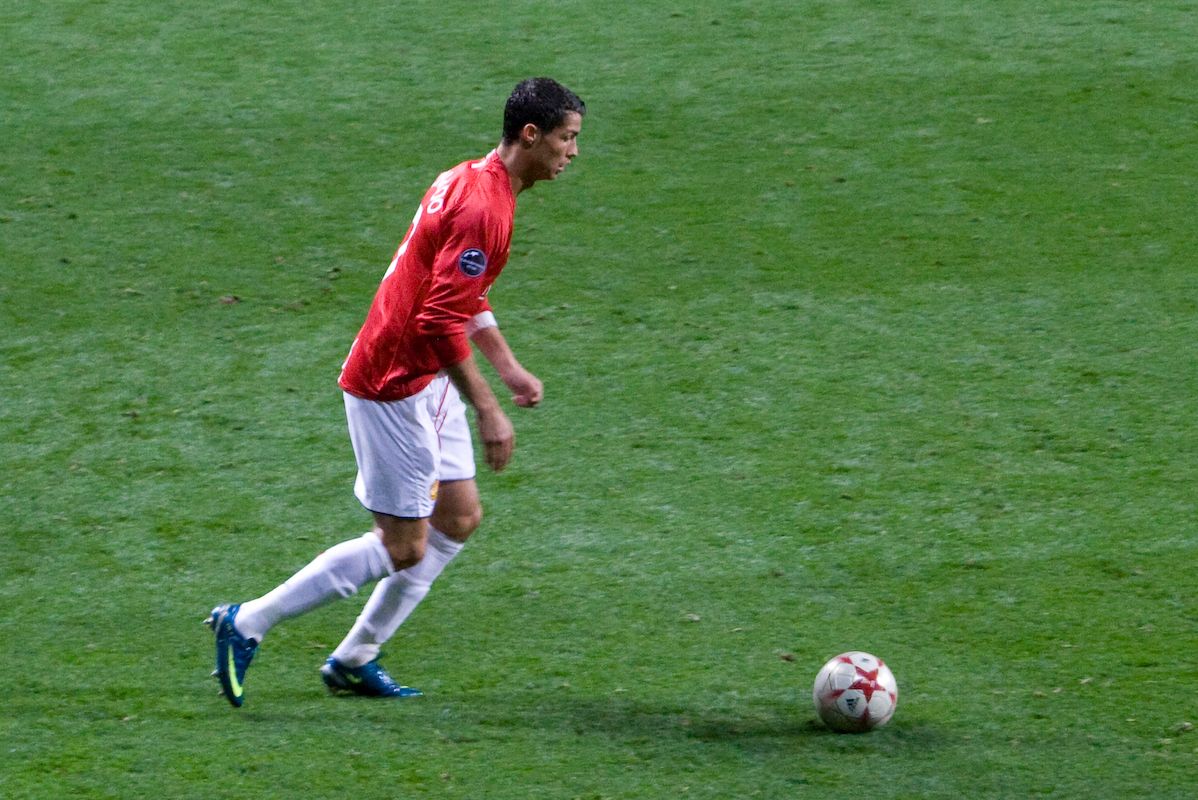 Cristiano Ronaldo conduzindo a bola com a camisa vermelha do Manchester United